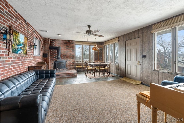 carpeted living room with a wealth of natural light, a textured ceiling, and a wood stove