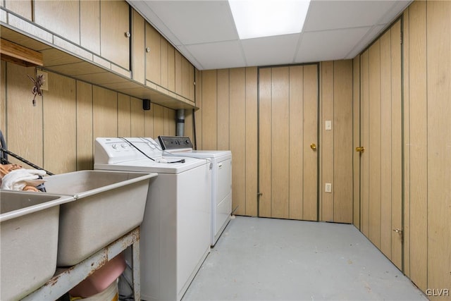 laundry area with washing machine and dryer, cabinets, and wood walls