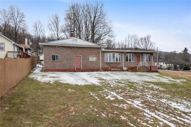 snow covered rear of property featuring a lawn