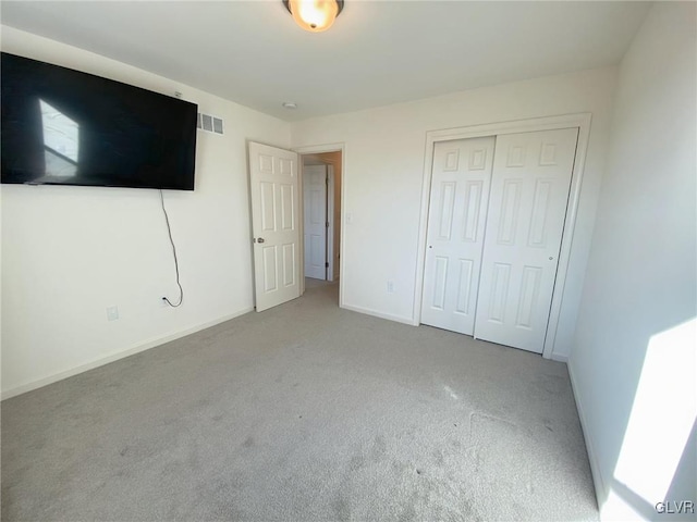 unfurnished bedroom with light colored carpet and a closet