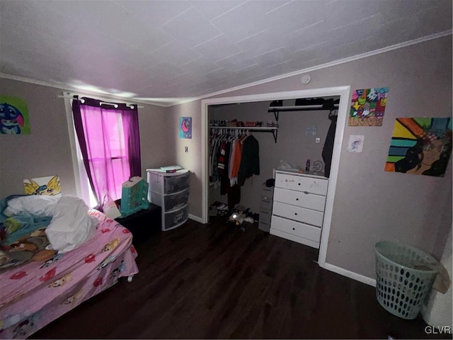 bedroom with dark hardwood / wood-style flooring, vaulted ceiling, ornamental molding, and a closet