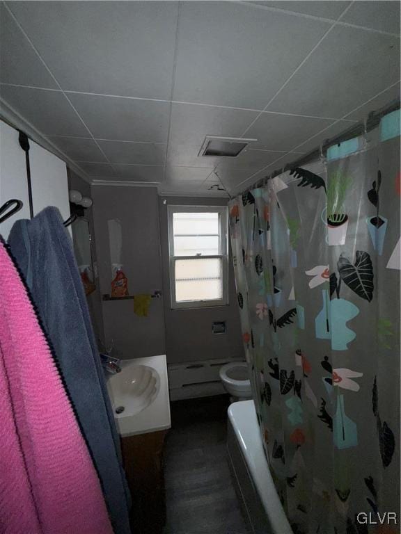 full bathroom with a paneled ceiling, vanity, shower / bath combination with curtain, a baseboard radiator, and toilet