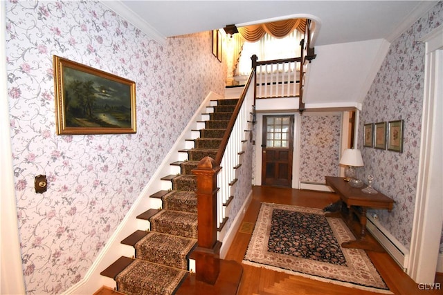 foyer entrance with baseboard heating, ornamental molding, and hardwood / wood-style floors