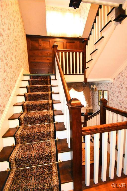 stairs with a high ceiling and ornamental molding