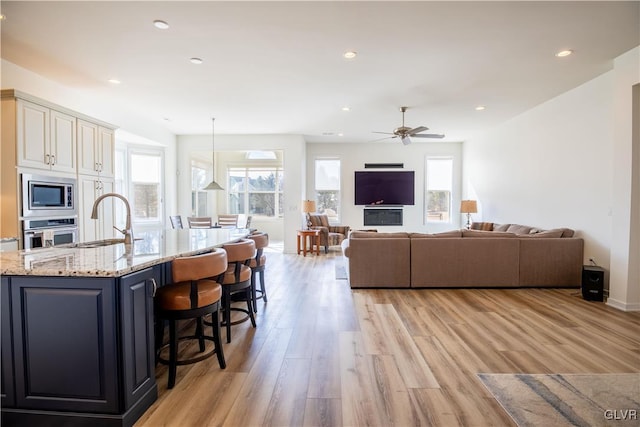 living room with a healthy amount of sunlight, sink, and light hardwood / wood-style flooring