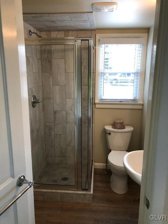 bathroom with toilet, a shower with door, and hardwood / wood-style floors