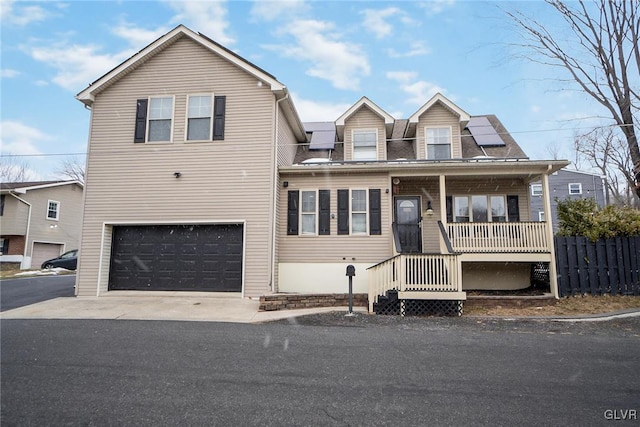 view of front of house with covered porch, solar panels, and a garage