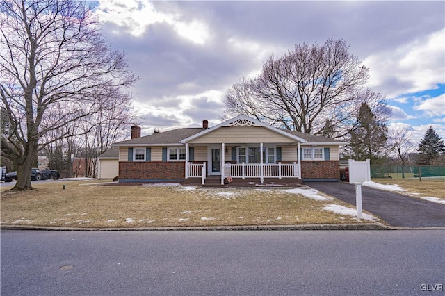 view of front of property featuring covered porch, a garage, and a front lawn