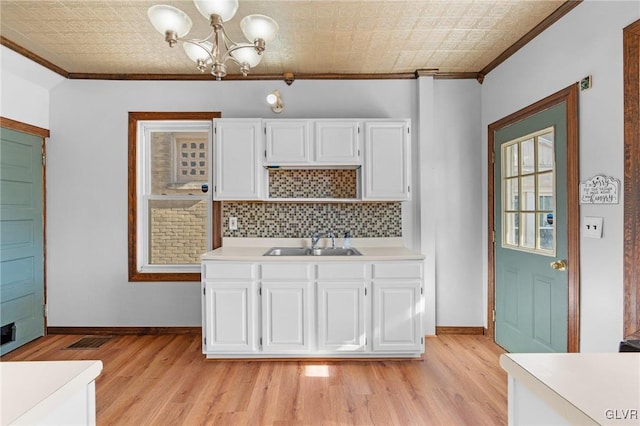 kitchen with sink, ornamental molding, backsplash, and white cabinetry