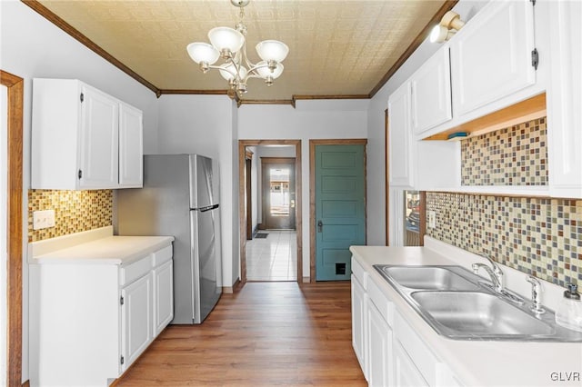 kitchen with ornamental molding, sink, white cabinets, and light hardwood / wood-style floors