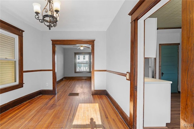 hall featuring wood-type flooring and a notable chandelier