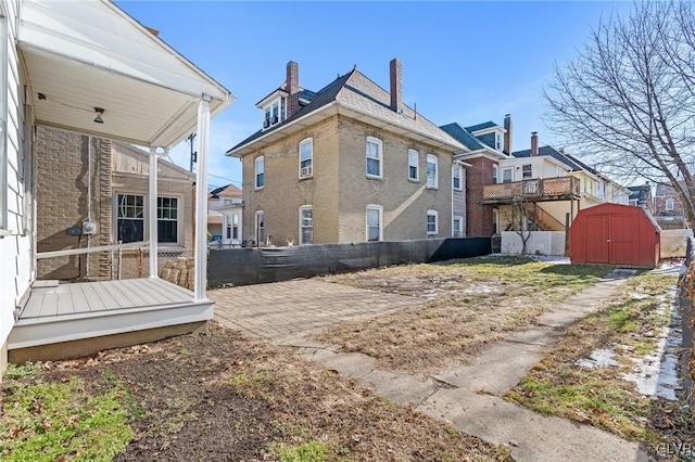 rear view of property with a patio and a storage shed