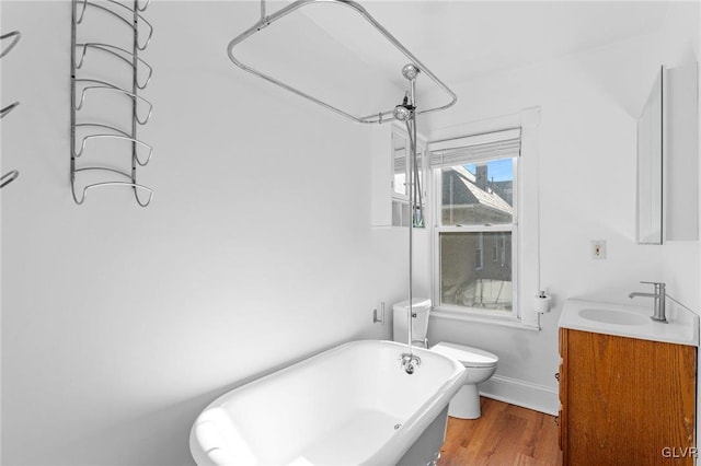 bathroom featuring a tub to relax in, toilet, vanity, and hardwood / wood-style floors