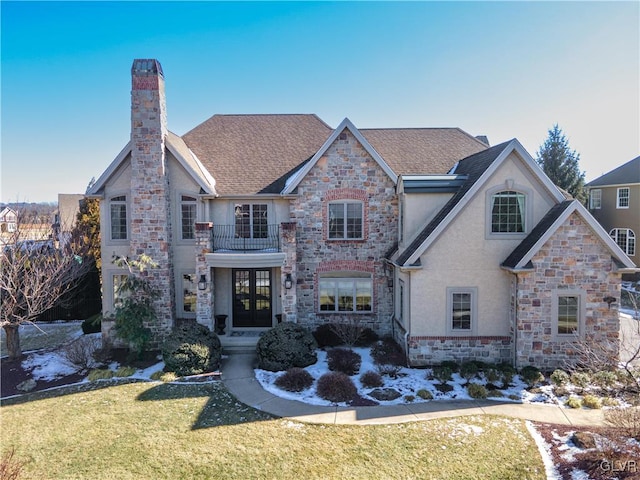 view of front of house with french doors, a balcony, and a front lawn