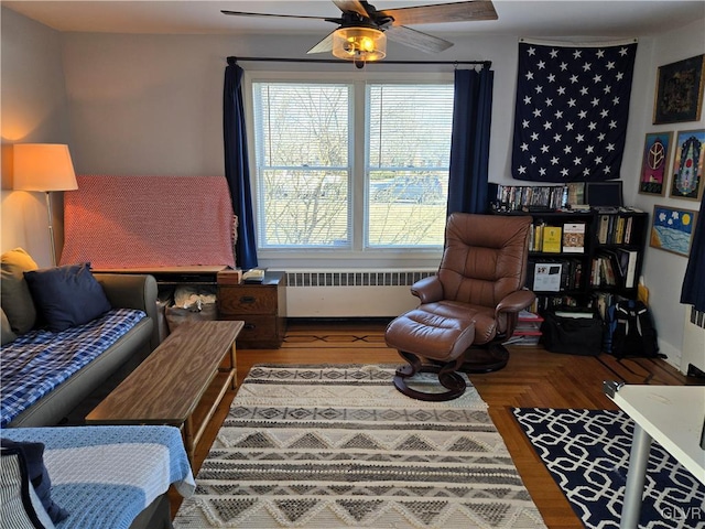 sitting room featuring ceiling fan, parquet floors, and radiator heating unit