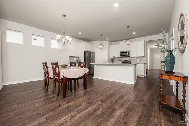 dining area with a chandelier, recessed lighting, dark wood finished floors, and baseboards