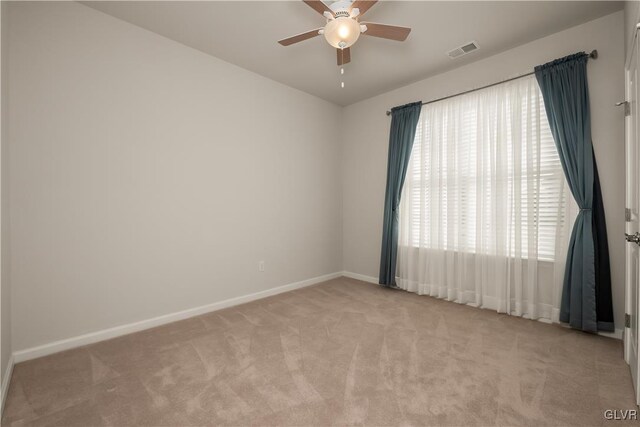 unfurnished room featuring baseboards, visible vents, a ceiling fan, and light colored carpet