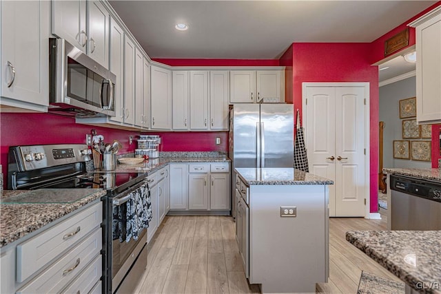 kitchen with stainless steel appliances, light stone countertops, and a center island