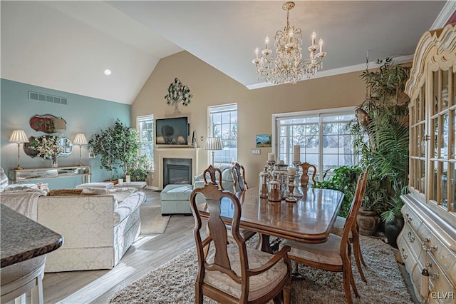 dining room featuring vaulted ceiling, an inviting chandelier, and light hardwood / wood-style flooring