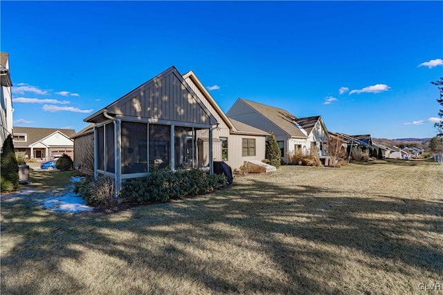 rear view of property featuring a yard and a sunroom