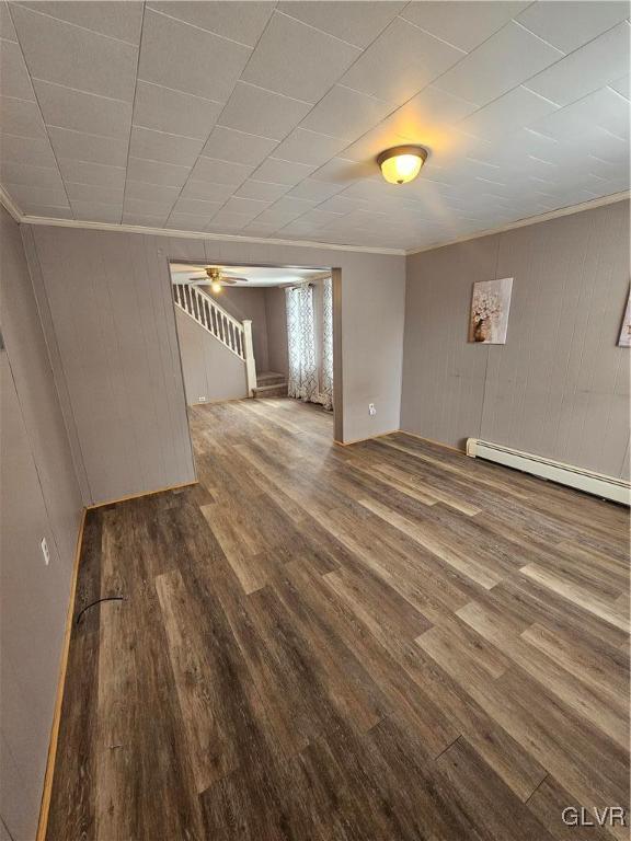 basement with ornamental molding, wood-type flooring, and a baseboard heating unit