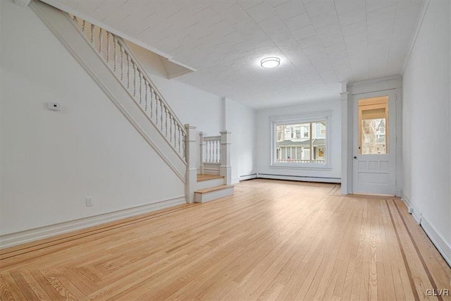 unfurnished living room featuring light wood-style flooring, stairs, a baseboard heating unit, and baseboards