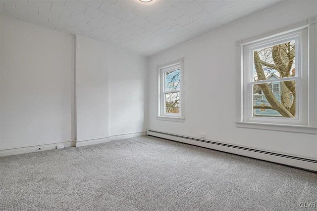 carpeted spare room with a baseboard heating unit