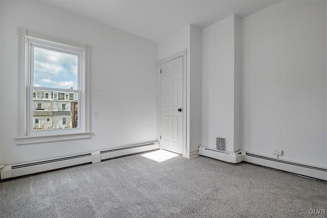 carpeted spare room with a baseboard heating unit