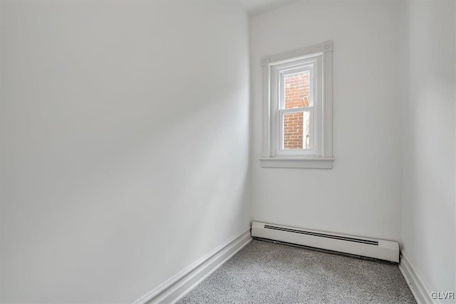 carpeted empty room with a baseboard heating unit and baseboards