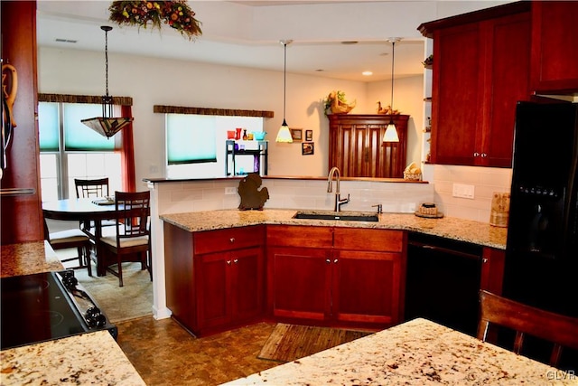 kitchen with decorative light fixtures, black appliances, light stone countertops, sink, and tasteful backsplash