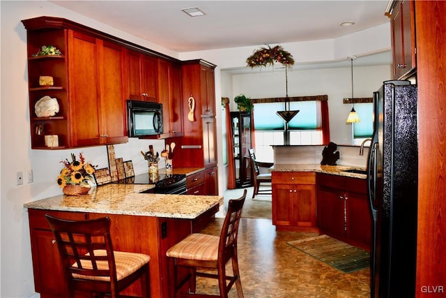 kitchen with light stone countertops, black appliances, pendant lighting, a kitchen bar, and kitchen peninsula