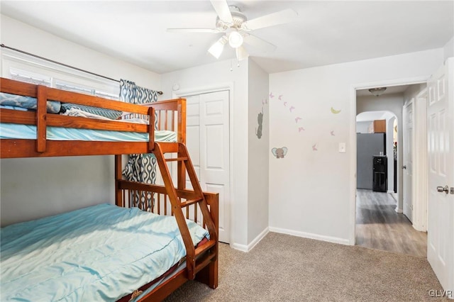 bedroom featuring ceiling fan, light carpet, and stainless steel refrigerator with ice dispenser