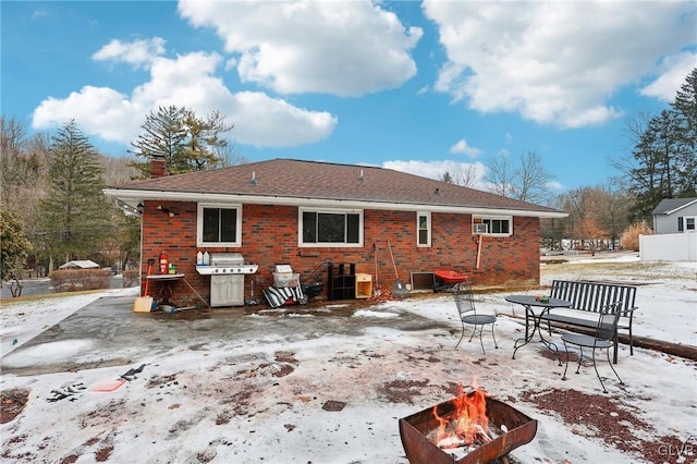 snow covered rear of property featuring an outdoor fire pit