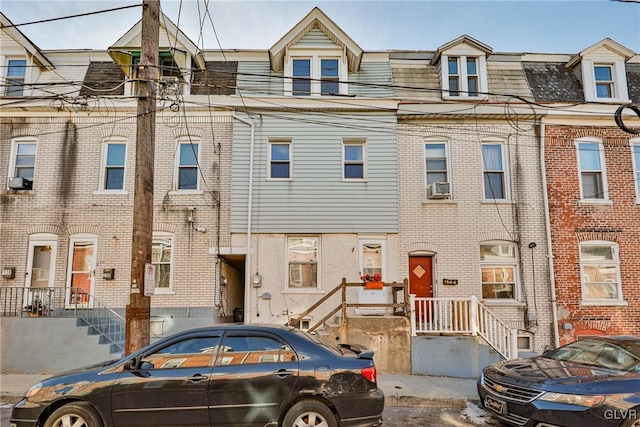 multi unit property featuring mansard roof, brick siding, and cooling unit