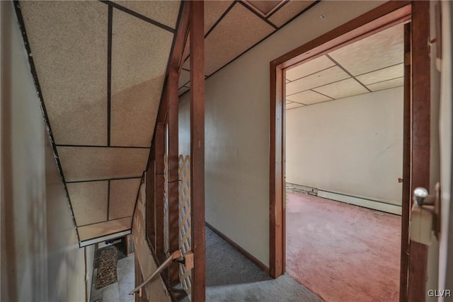 corridor featuring carpet, a paneled ceiling, and a baseboard heating unit