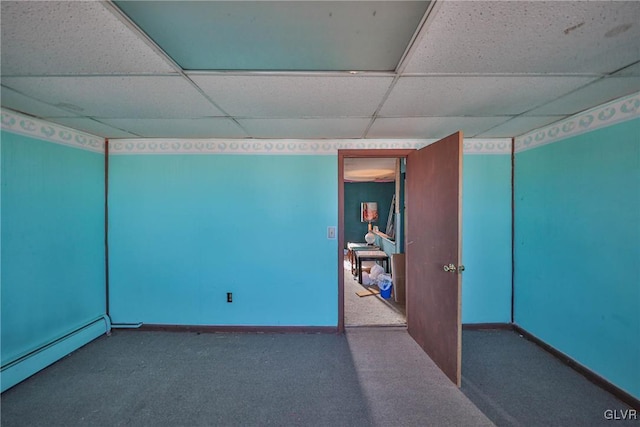 empty room featuring a baseboard radiator, carpet floors, and a drop ceiling