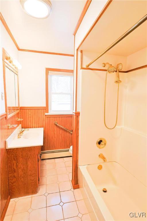 full bathroom with vanity, washtub / shower combination, a baseboard heating unit, crown molding, and toilet