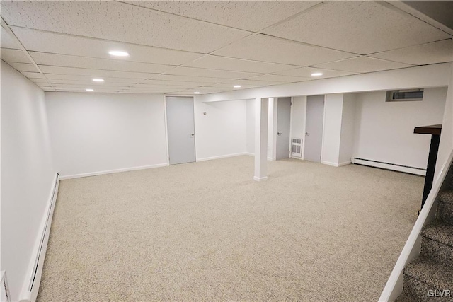 basement with a paneled ceiling, carpet flooring, and a baseboard radiator