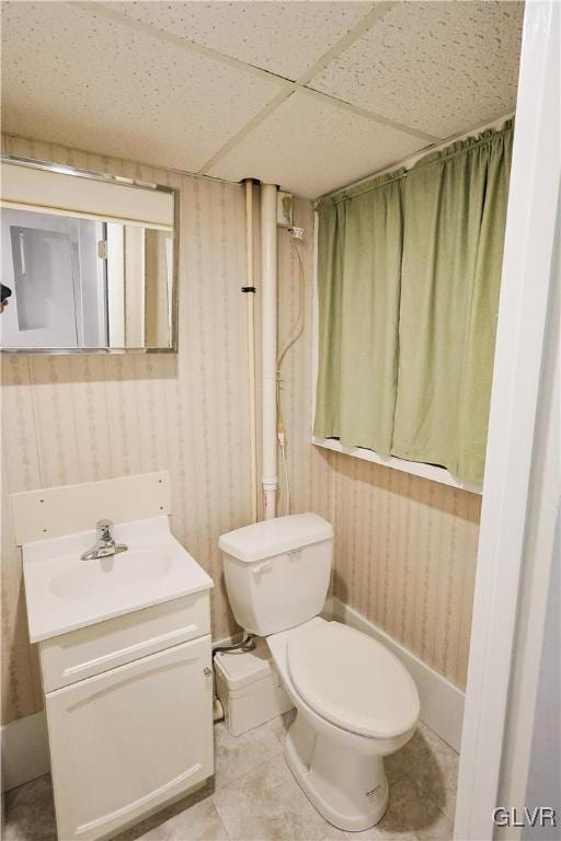 bathroom featuring a drop ceiling, vanity, tile patterned flooring, and toilet