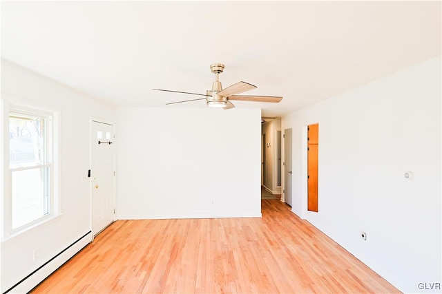 empty room featuring ceiling fan, light hardwood / wood-style flooring, and a baseboard heating unit