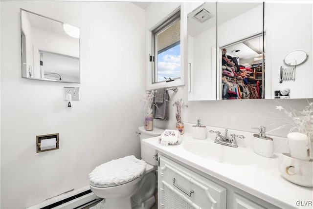 bathroom featuring toilet, a baseboard radiator, a walk in closet, and vanity