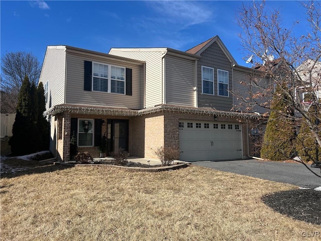 traditional-style home featuring an attached garage, a front yard, aphalt driveway, and brick siding