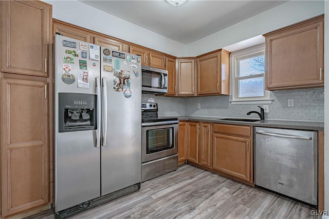 kitchen with brown cabinetry, light wood-style flooring, stainless steel appliances, and decorative backsplash