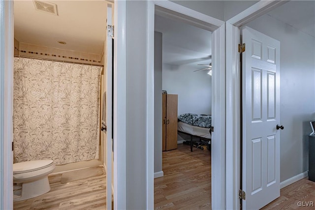 bathroom featuring visible vents, toilet, ceiling fan, wood finished floors, and a shower with curtain