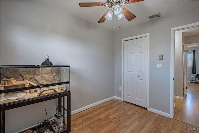 office area with ceiling fan, light wood-type flooring, visible vents, and baseboards