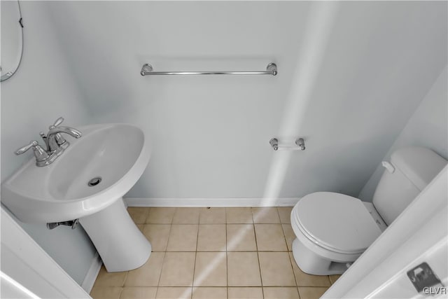 half bath featuring baseboards, toilet, and tile patterned floors