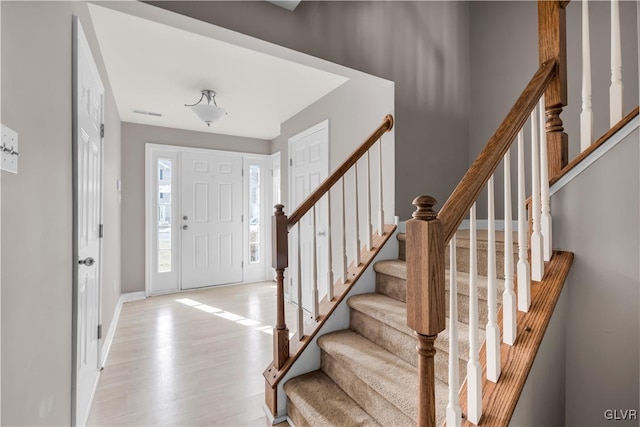 entryway with light wood-style flooring, stairs, and baseboards