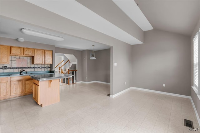 kitchen with a breakfast bar, pendant lighting, dark countertops, backsplash, and a peninsula