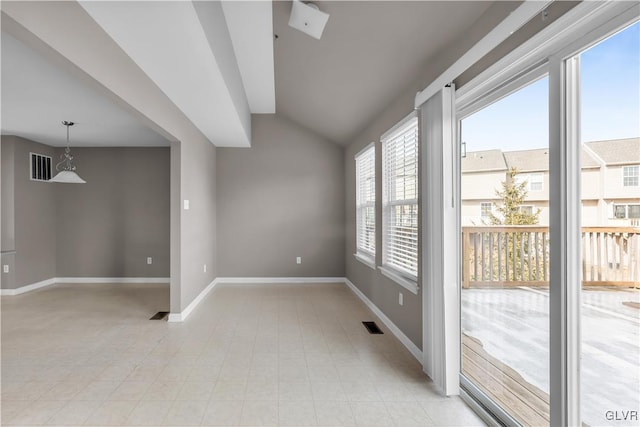 empty room featuring vaulted ceiling, visible vents, and baseboards