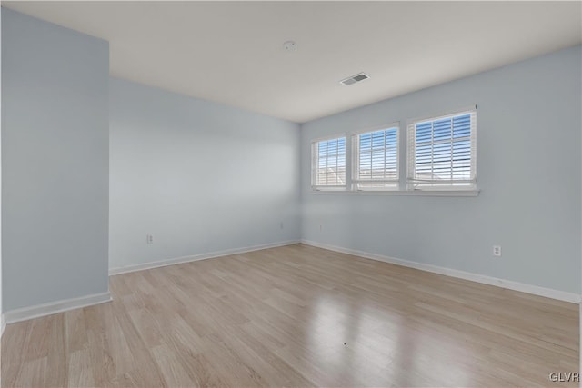 spare room with light wood-style floors, visible vents, and baseboards